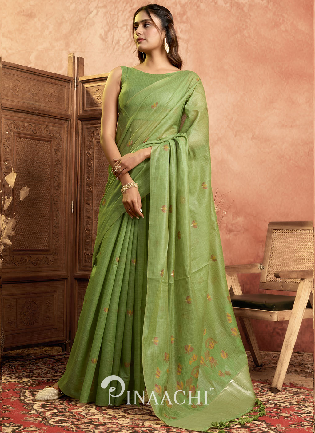 Pinaachi green jamdani saree with subtle floral motifs worn by a woman in an elegant traditional setting