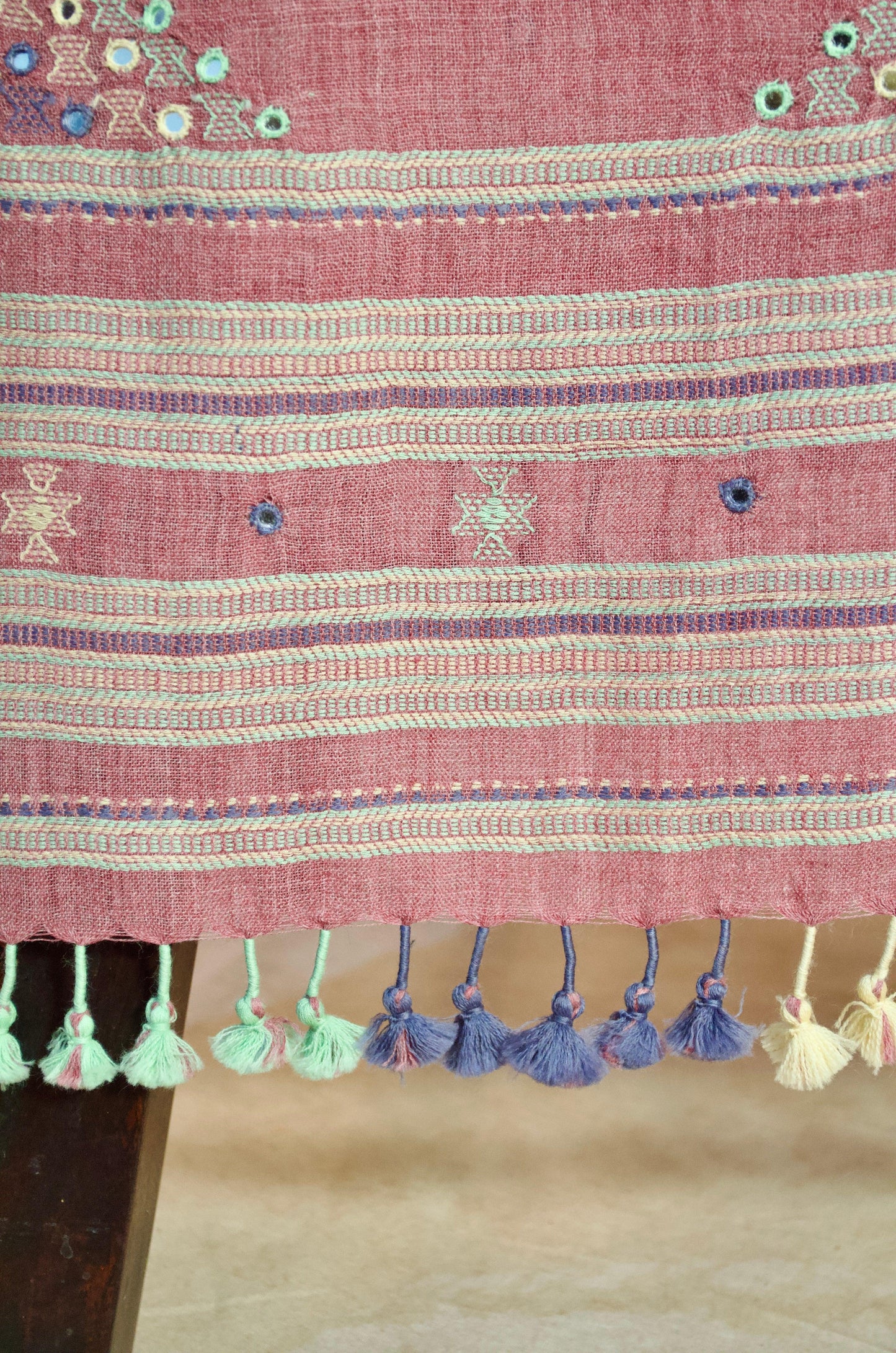 Handwoven merino wool stole with intricate embroidery and colorful tassels at the hem