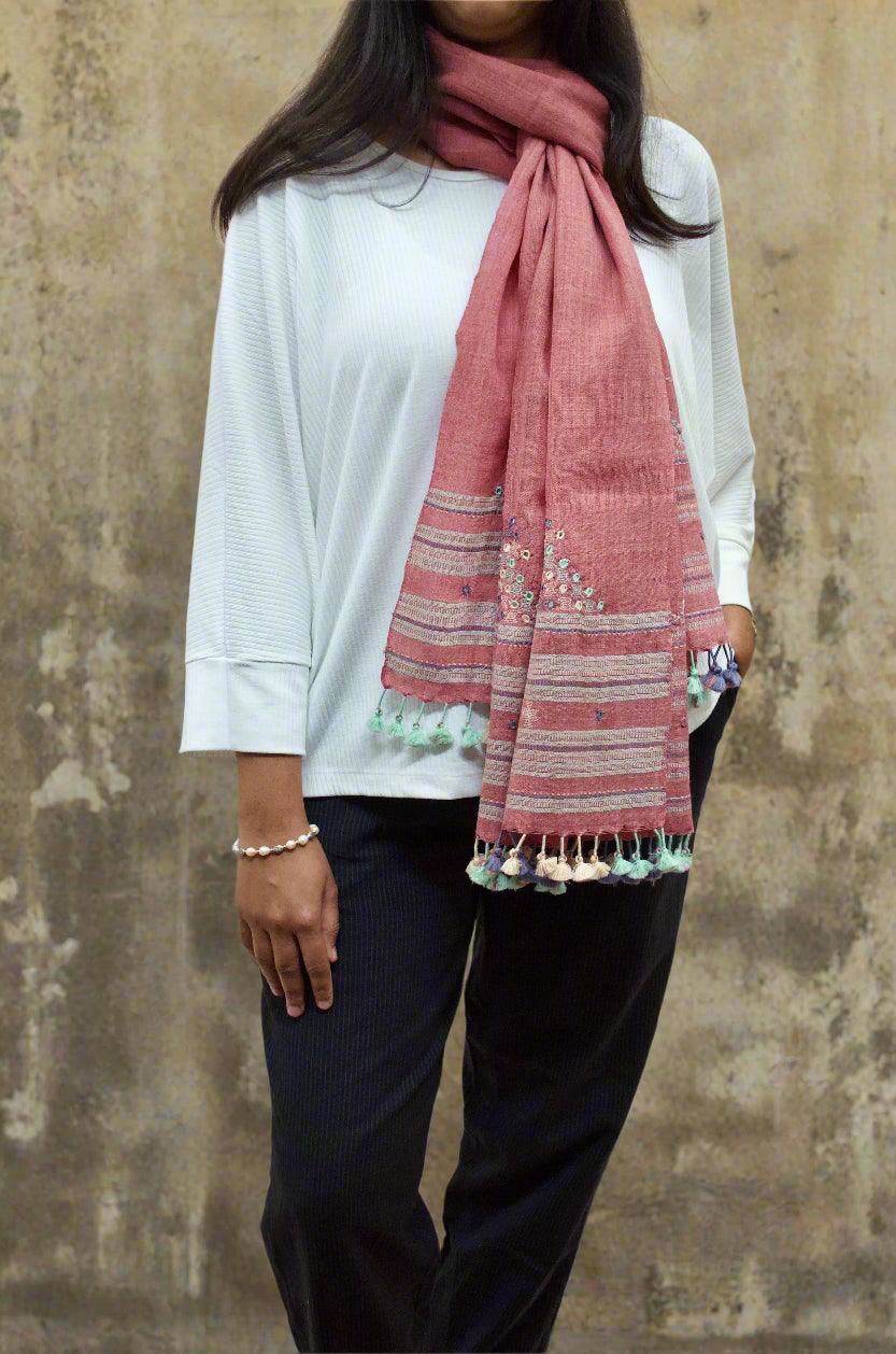 Stylish woman wearing a handwoven merino wool stole in pink with decorative tassels