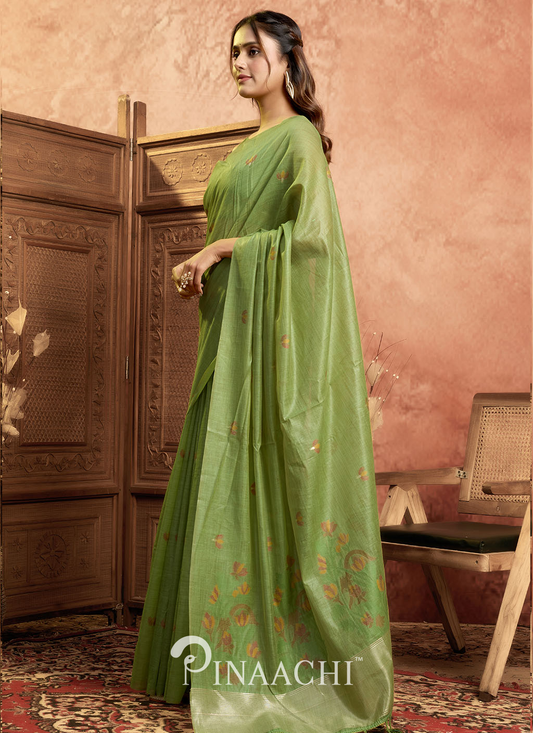 Pinaachi green jamdani saree with delicate floral patterns worn by a woman in a traditional setting