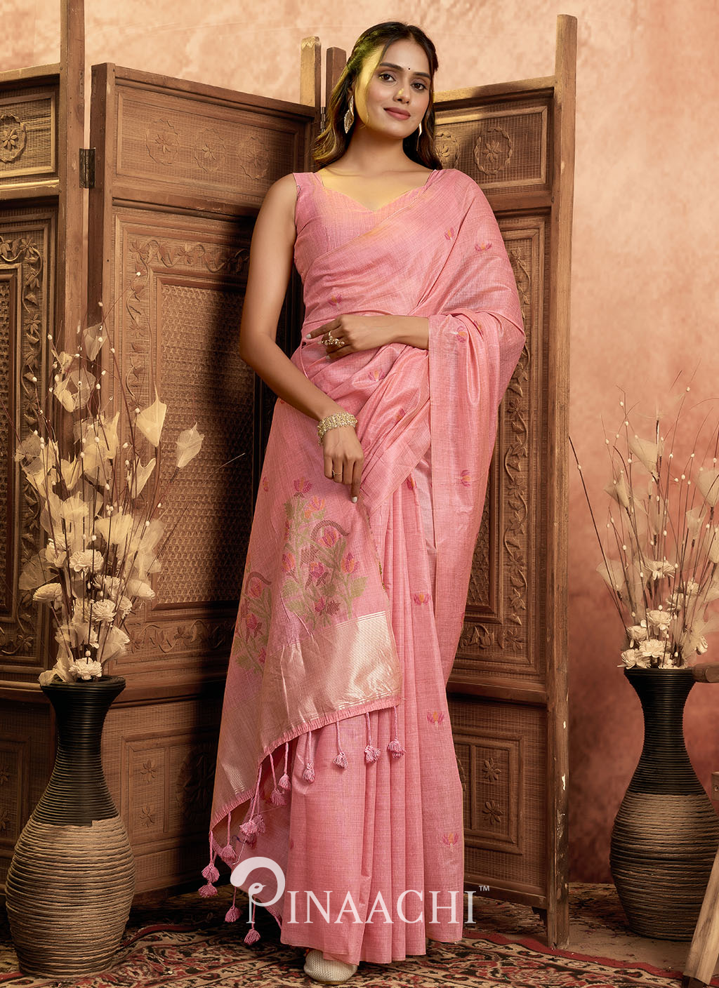 Pinaachi pink jamdani saree with floral design and tassels worn by woman in elegant setting
