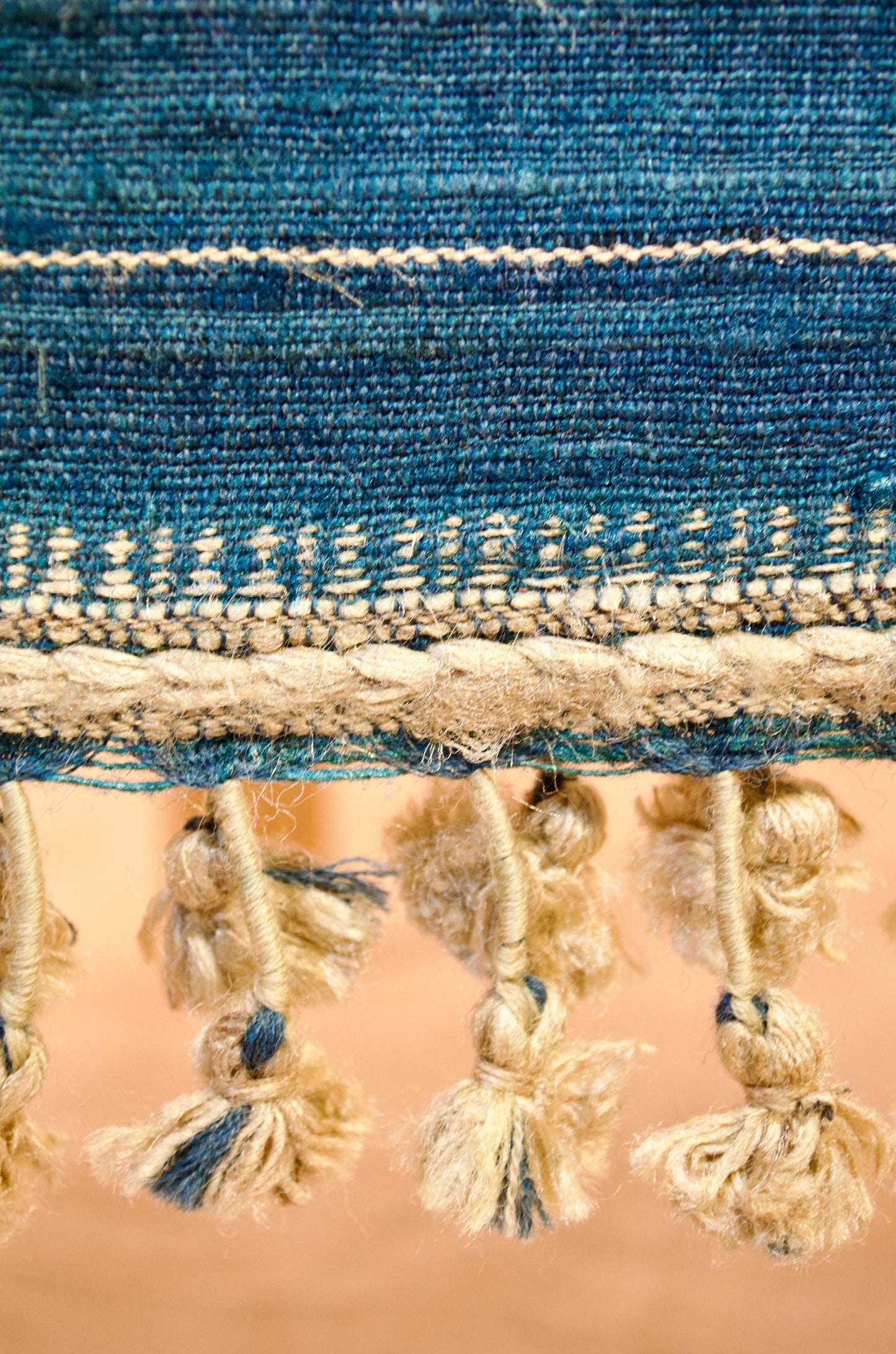 Close-up of a merino wool indigo shawl featuring decorative tassels and intricate weaving patterns