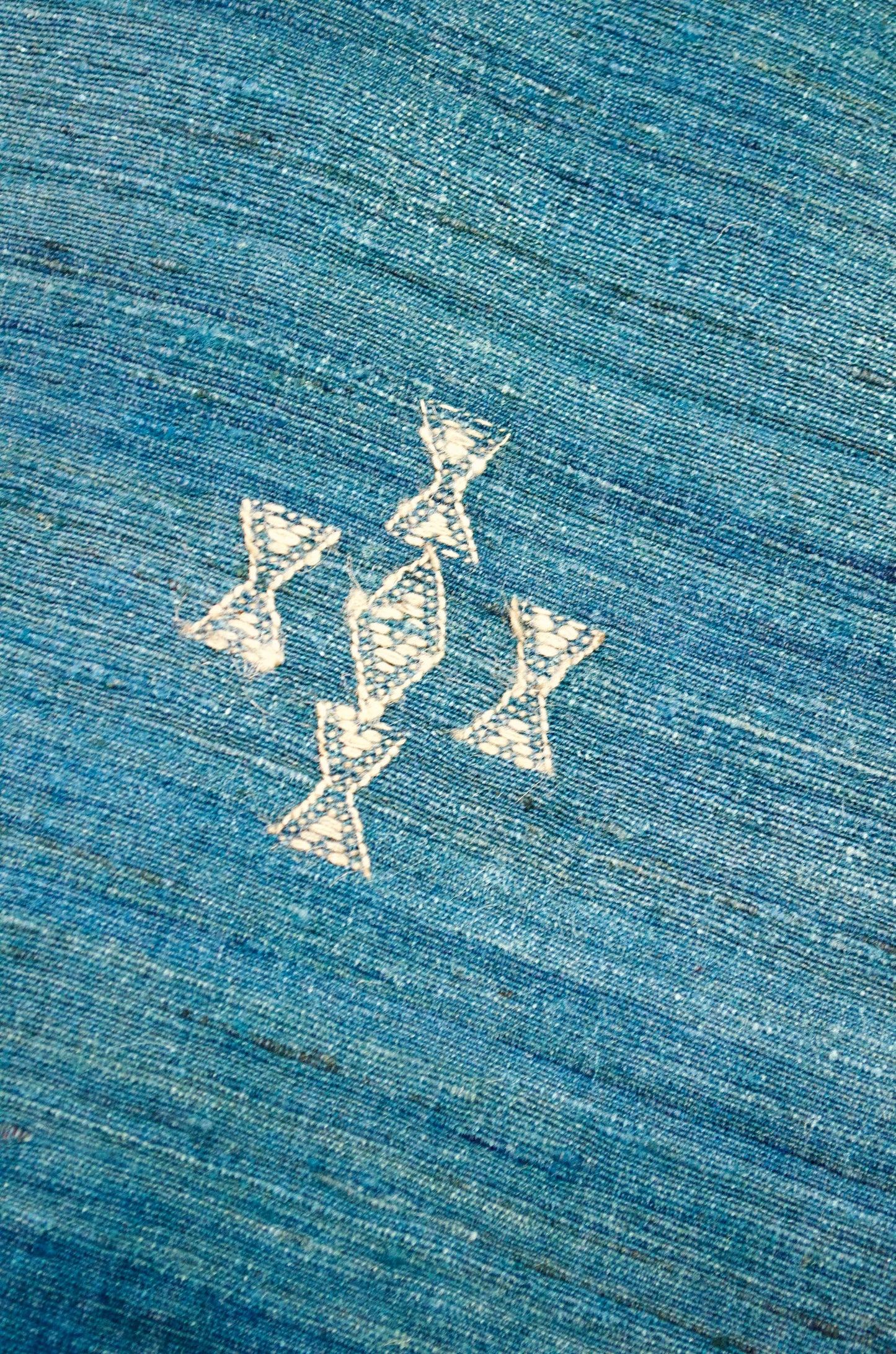 Close-up of intricate designs on a merino wool indigo shawl featuring elegant embroidery