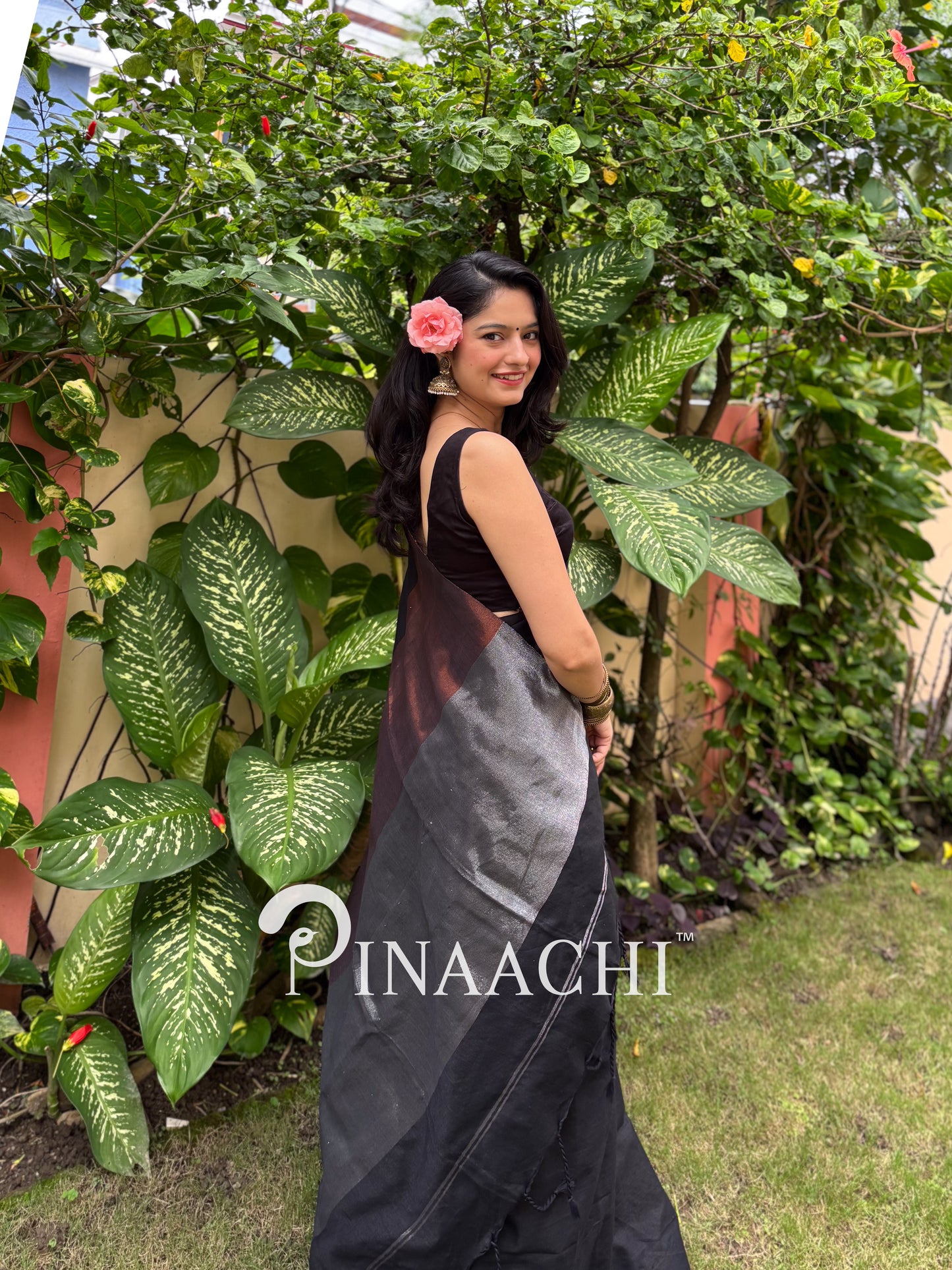 Elegant black cotton saree with zari border showcased by a model in a garden setting