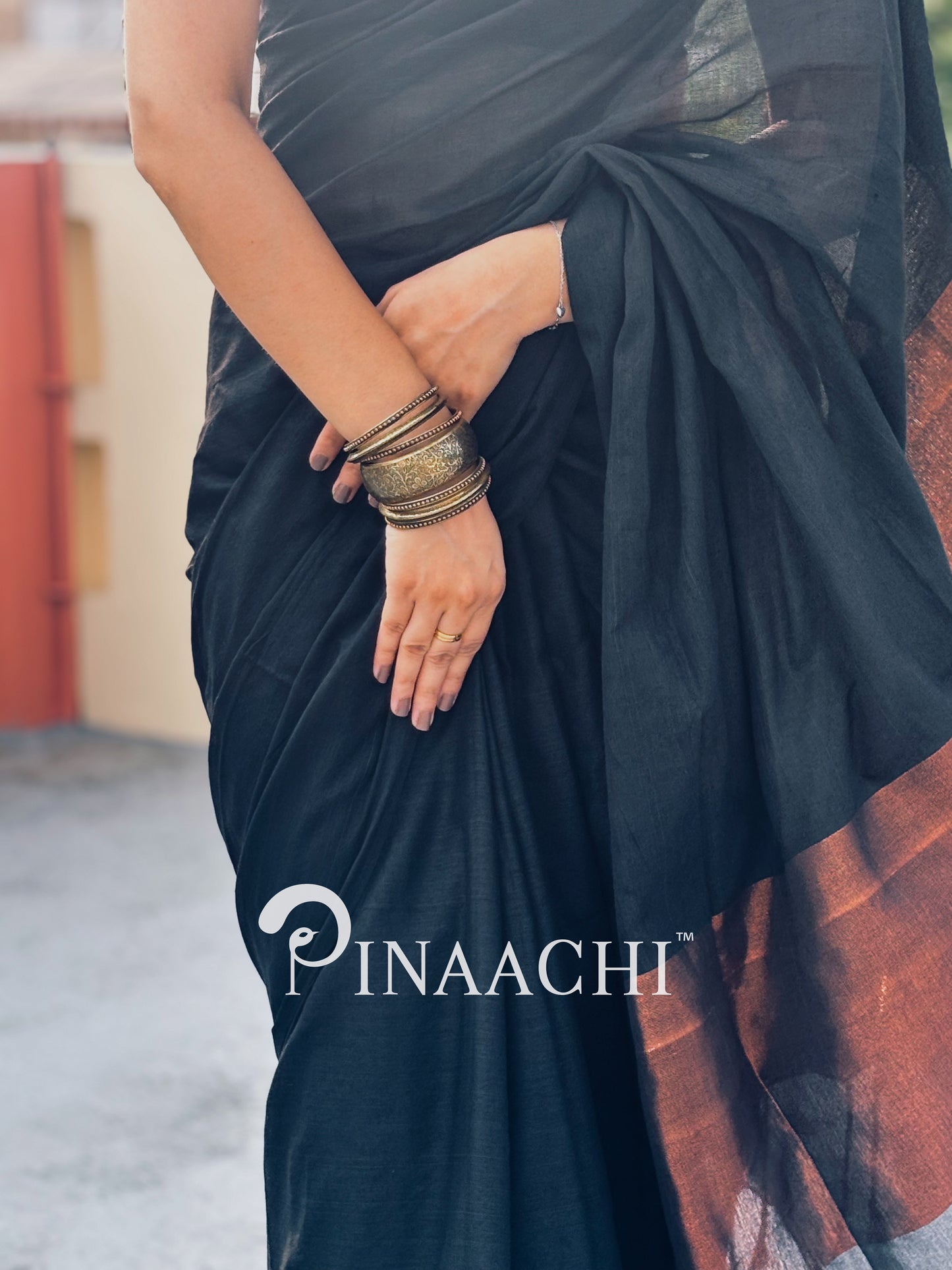 Elegant black cotton saree with zari border showcased by a model, featuring intricate designs and accessories