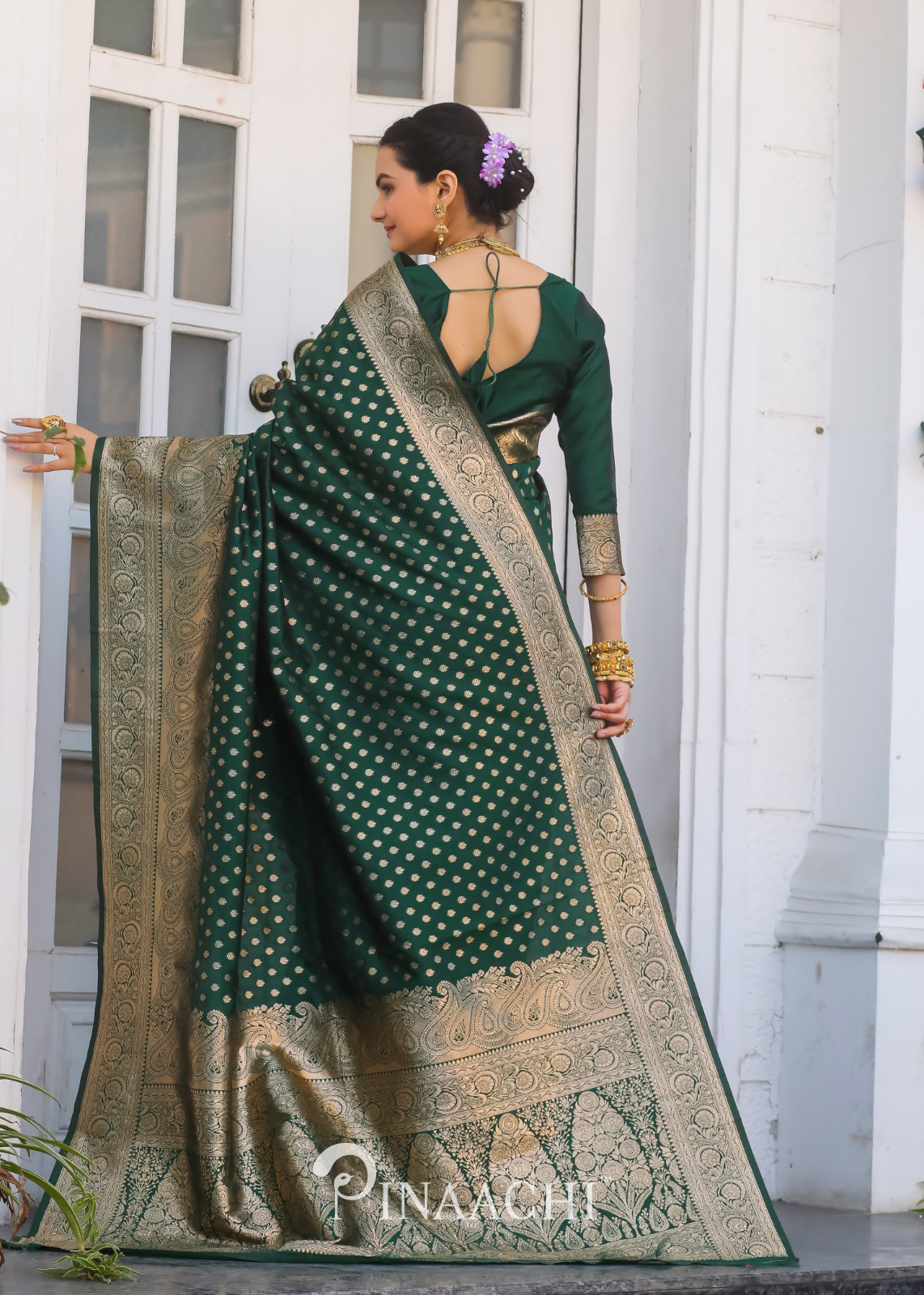 Woman wearing Pinaachi bottle green Banarasi saree with intricate gold zari work and traditional design