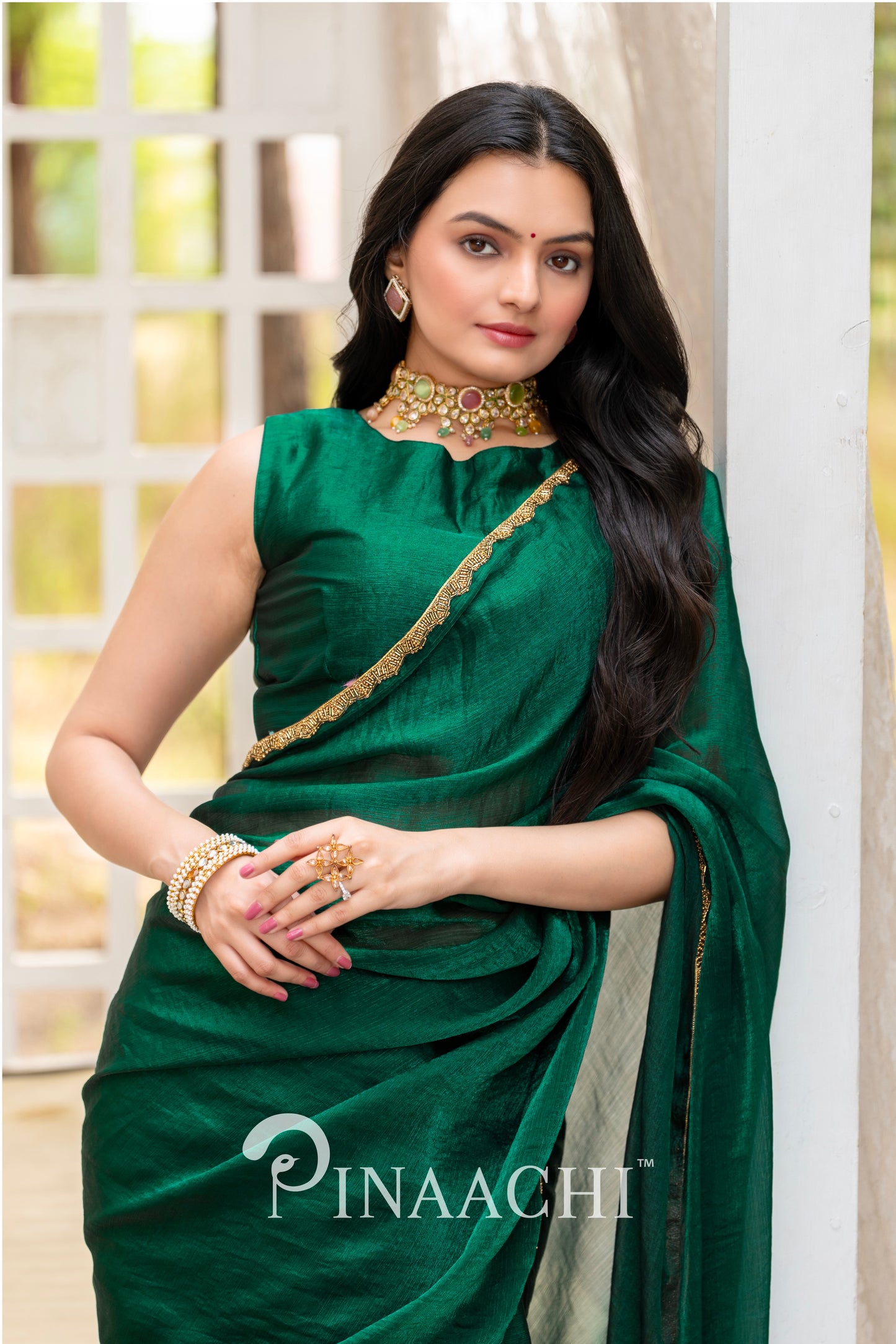 Woman wearing a Pinaachi bottle green chiffon saree with gold border and matching blouse