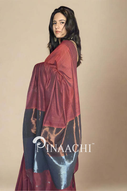 Model wearing a brick red cotton saree with zari showcasing elegant draping style