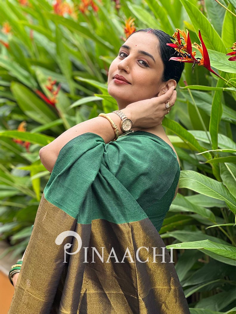 Elegant woman wearing an emerald green cotton saree with a beautiful gold border outdoors