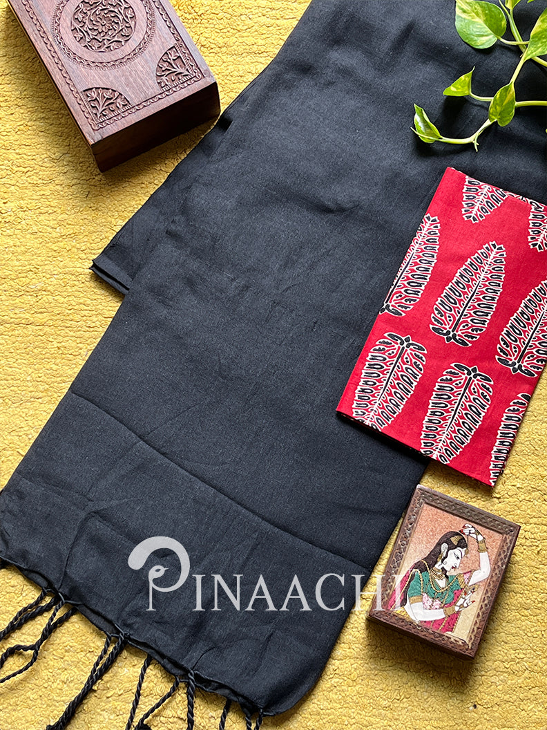 Handspun black cotton saree displayed with intricate red accessories on a yellow background