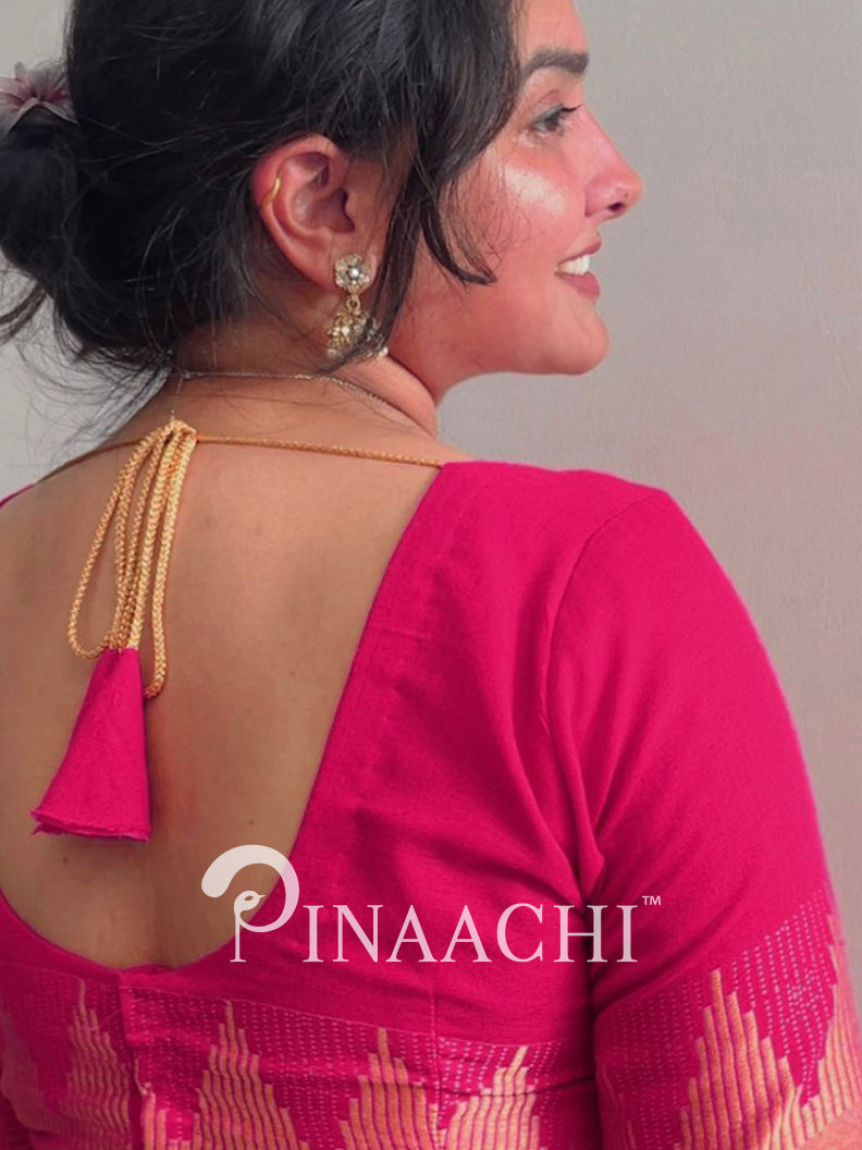 Woman wearing a bright pink saree with a visible brand logo on a plain background