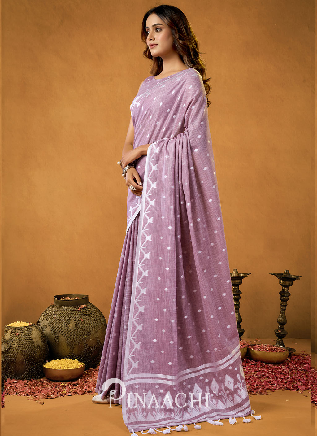 Pinaachi jamdani saree in lavender with white intricate patterns worn by a woman in traditional setting
