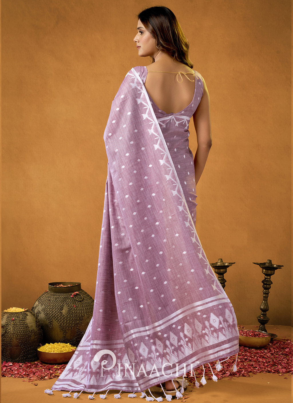 Woman wearing a pink Pinaachi Jamdani saree with white traditional patterns and tassels on the pallu