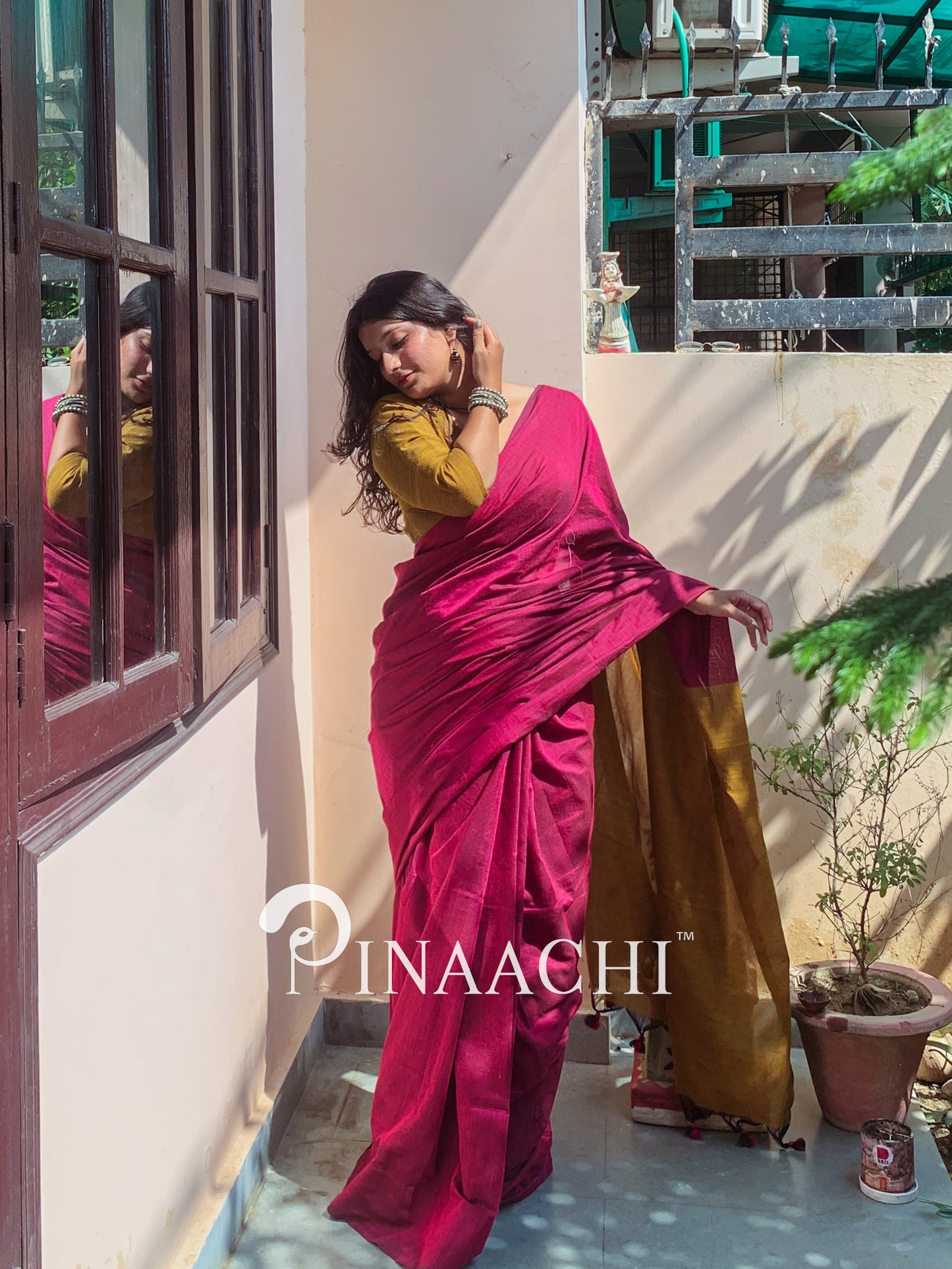 Model wearing a magenta pink cotton handloom saree draped elegantly in natural light