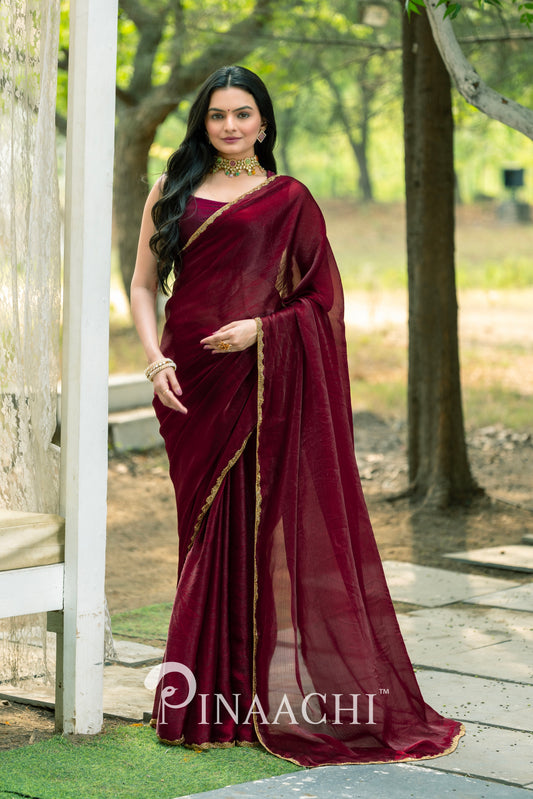 Woman wearing Pinaachi maroon chiffon saree with gold border standing outdoors in natural setting
