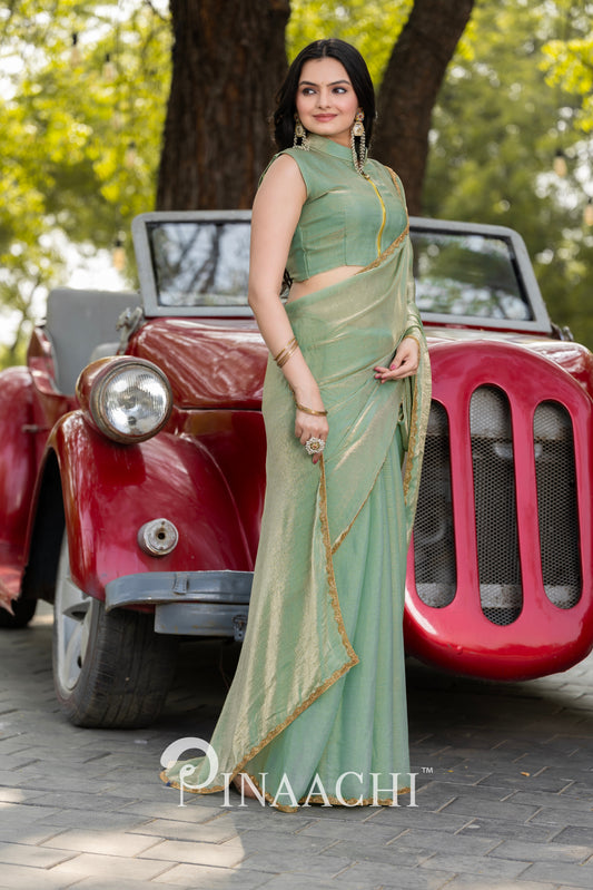 Woman wearing pinaachi pista green chiffon saree standing in front of a vintage red car outdoors