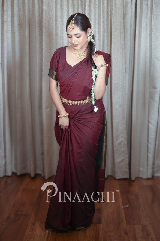 Elegant model draped in plum wine cotton saree handspun with gold accents and traditional jewelry