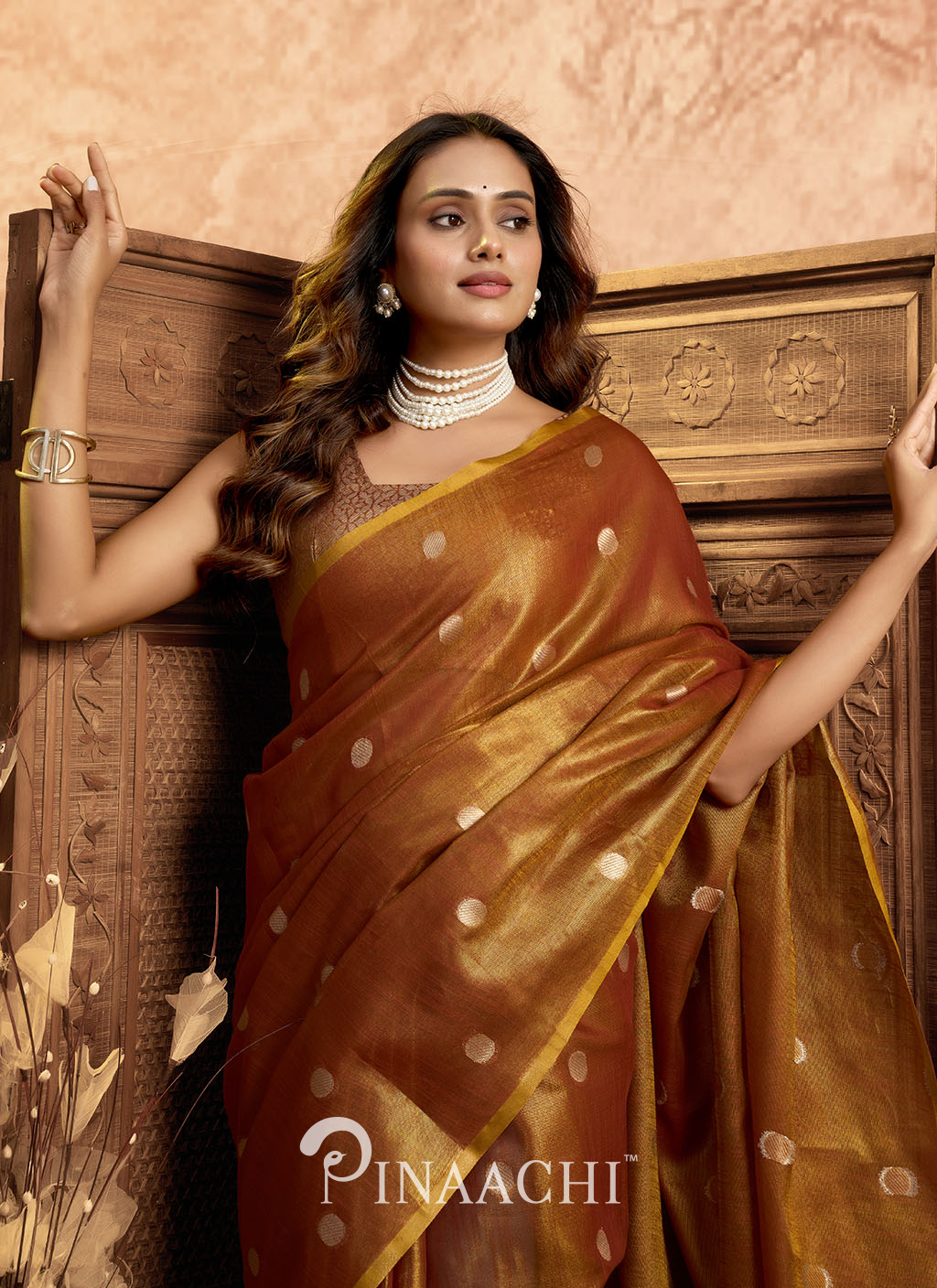 Elegant woman wearing a Pinaachi polka tissue silk saree in rich brown with gold polka dots and border