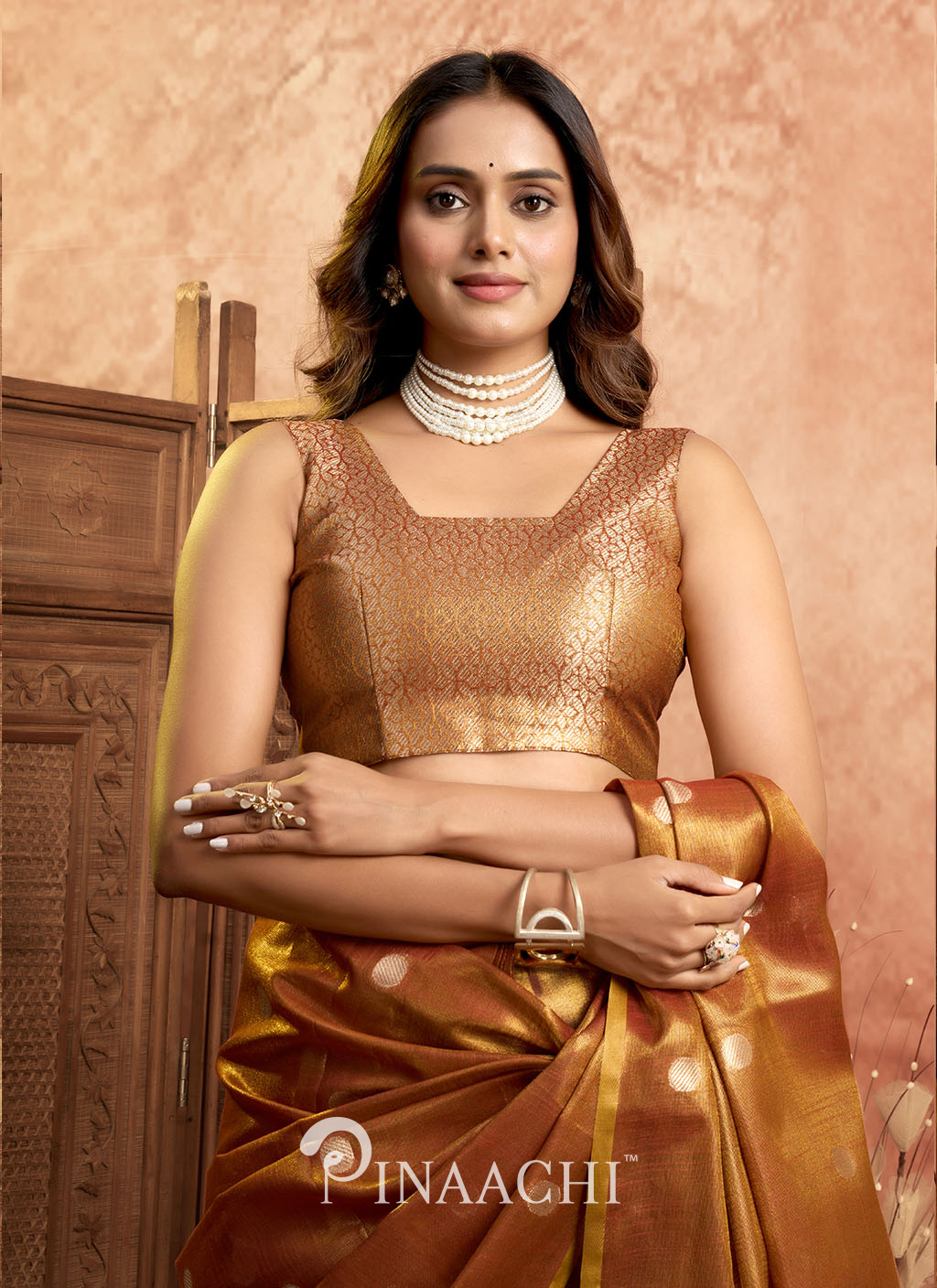 Woman wearing Pinaachi polka tissue silk saree in golden brown with intricate blouse and pearl jewelry