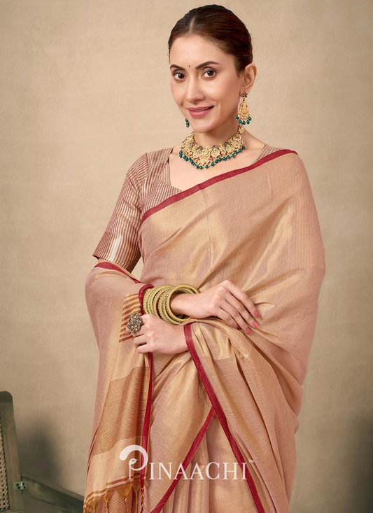 Elegant woman wearing a Pinaachi Pure Tissue Silk Saree in beige with maroon border and gold jewelry