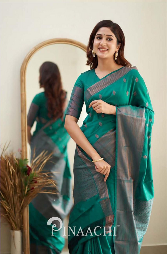 Woman wearing Pinaachi Rama Green Litchi Silk Saree with silver border posing near a mirror