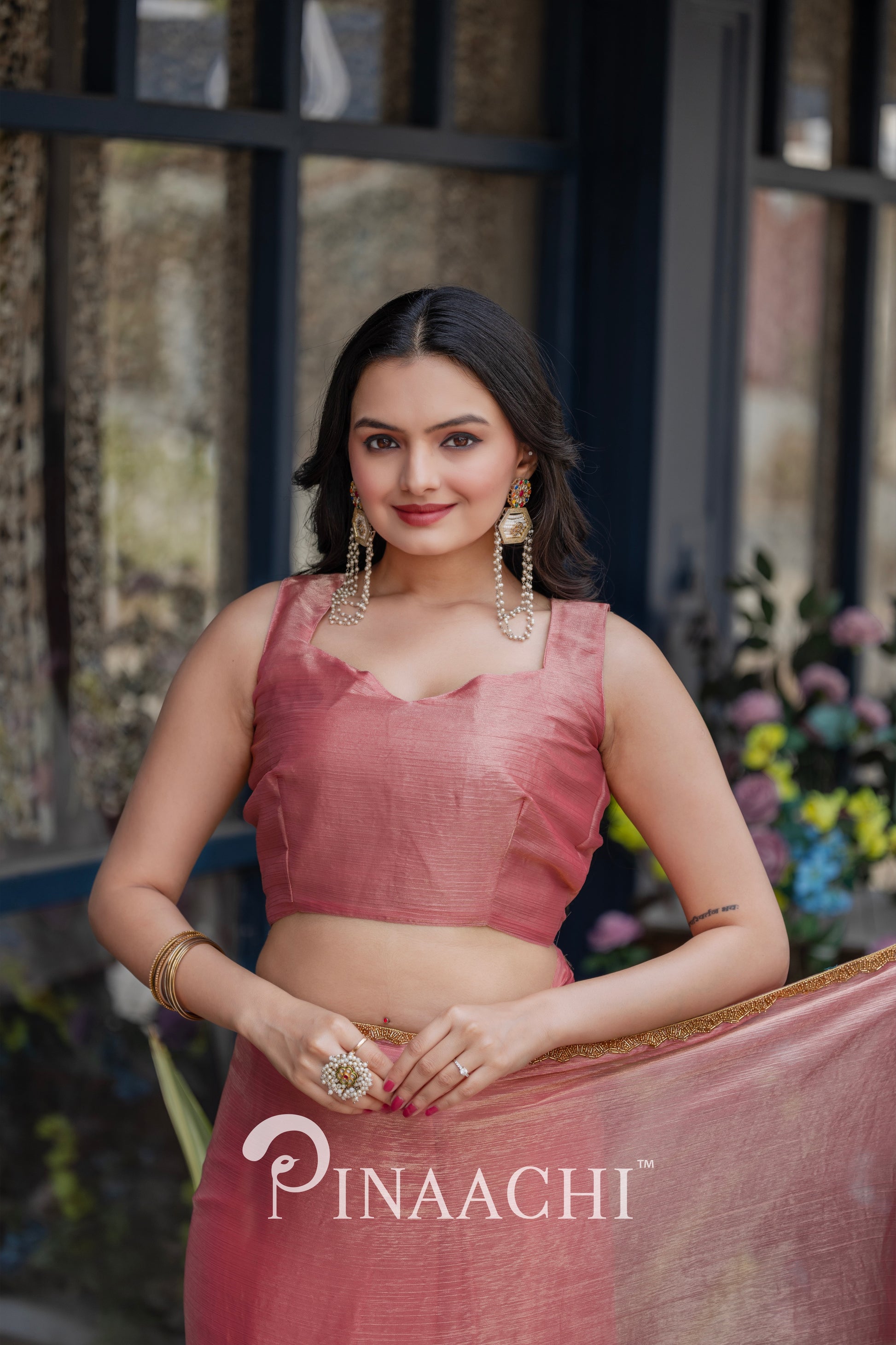 Woman wearing pinaachi solid pink chiffon saree with sleeveless blouse and gold accessories