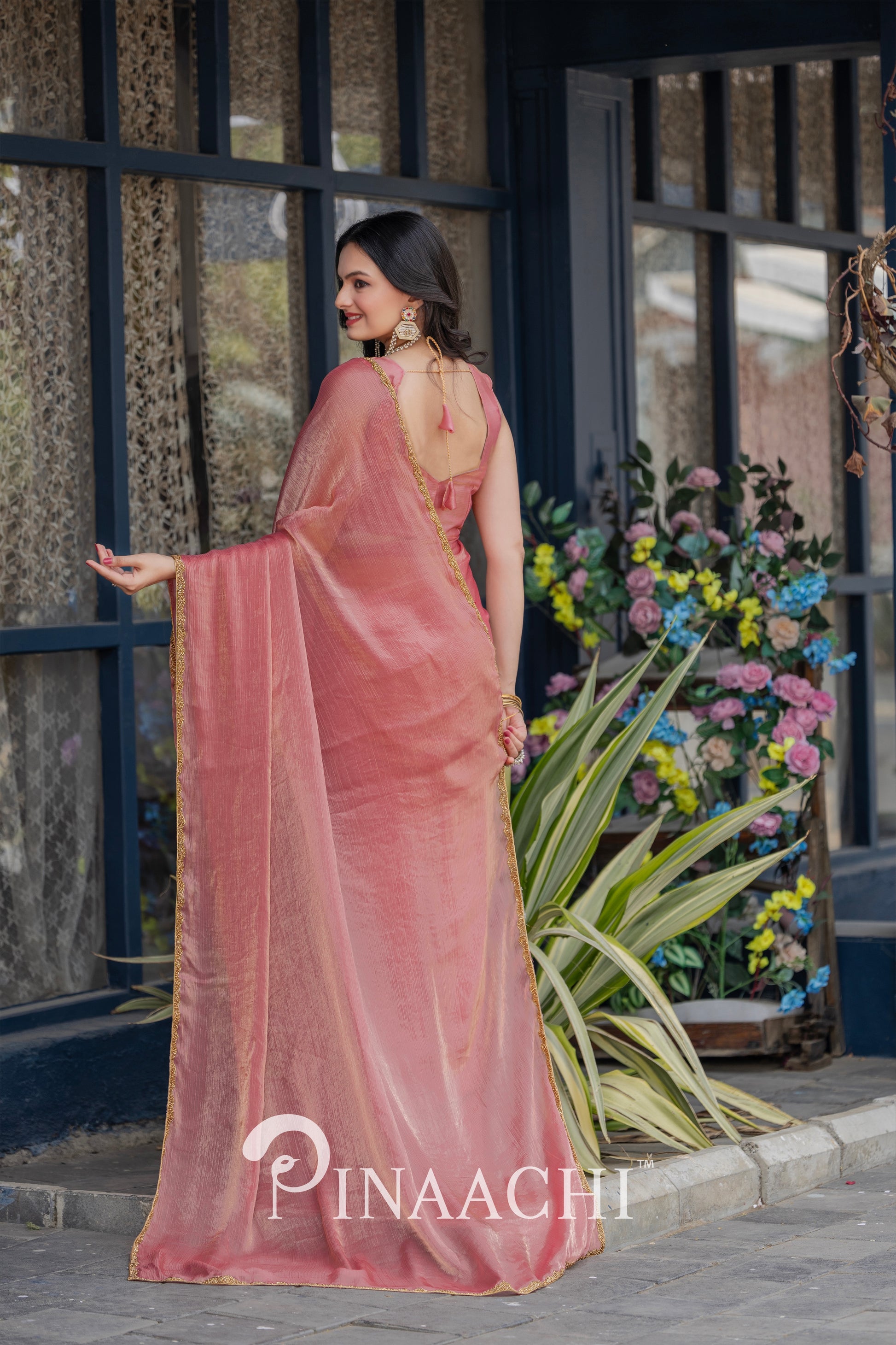 Pinaachi solid pink chiffon saree worn by model with floral background and elegant design