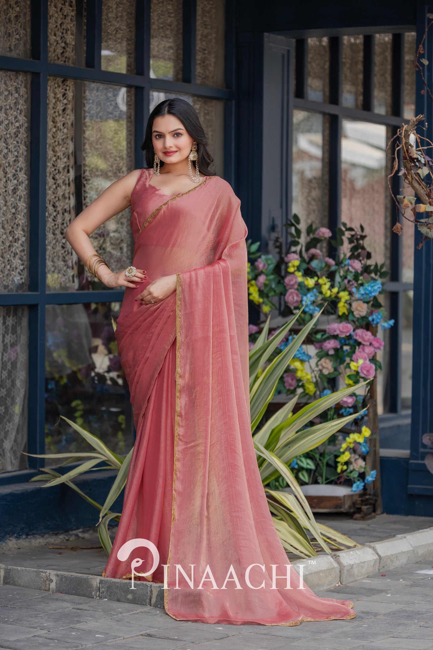 Pinaachi solid pink chiffon saree worn by woman with gold border and matching blouse