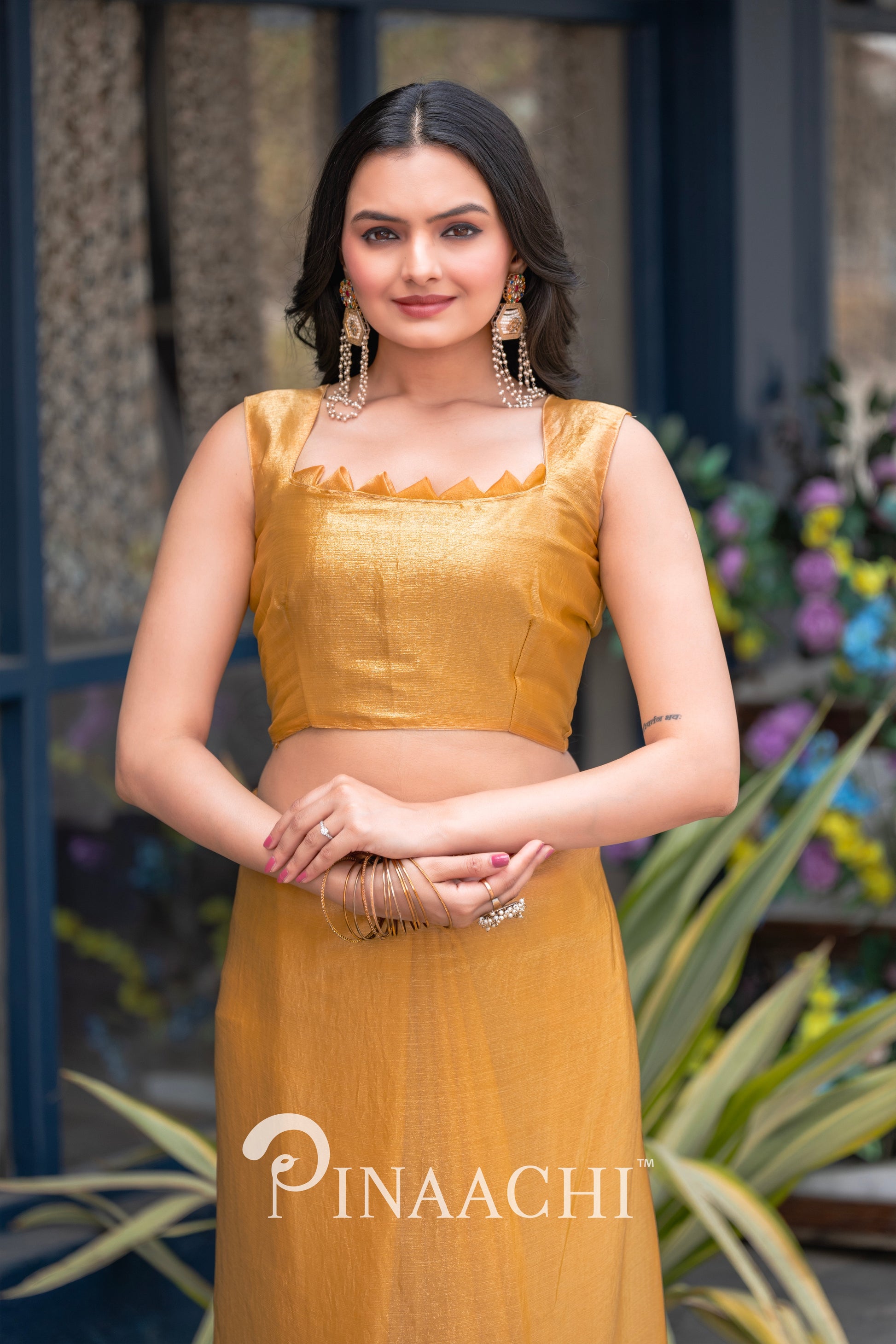 Woman wearing pinaachi solid yellow chiffon saree with sleeveless blouse and statement earrings