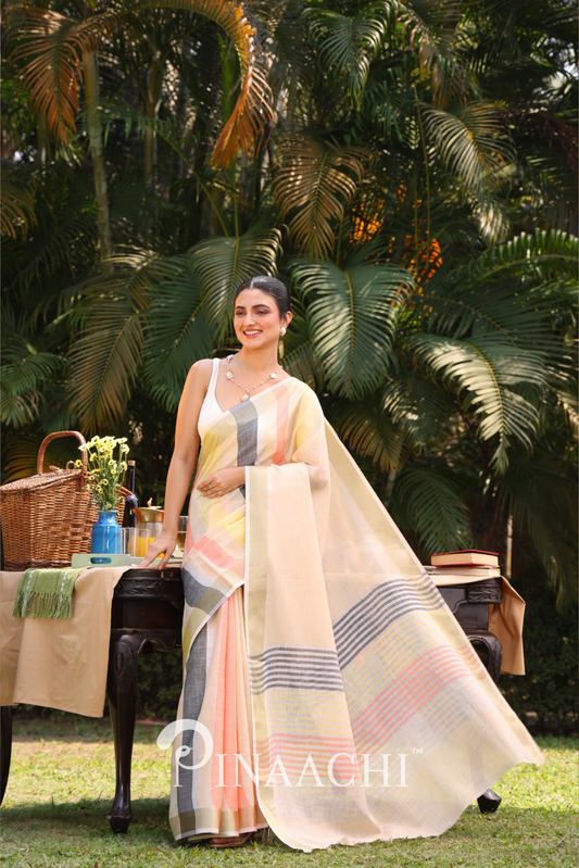 Woman wearing a Pinaachi striped linen silk saree in pastel colors standing outdoors with greenery background