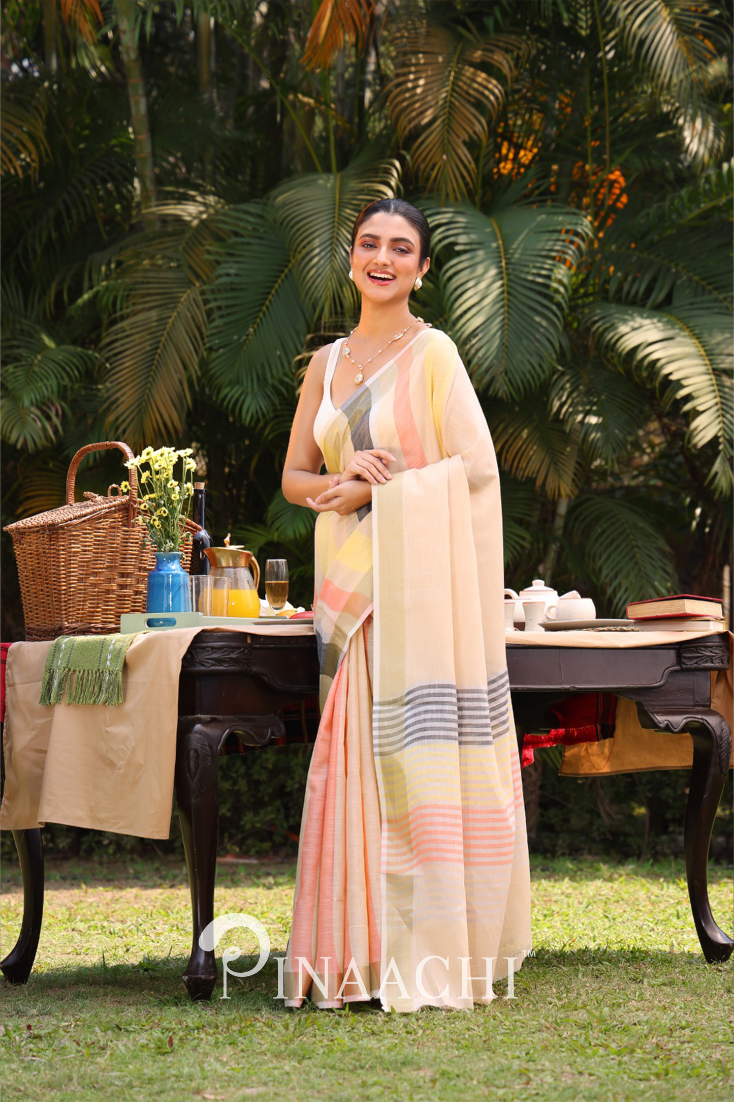 Pinaachi striped linen silk saree worn by woman standing outdoors near wooden table with picnic setup