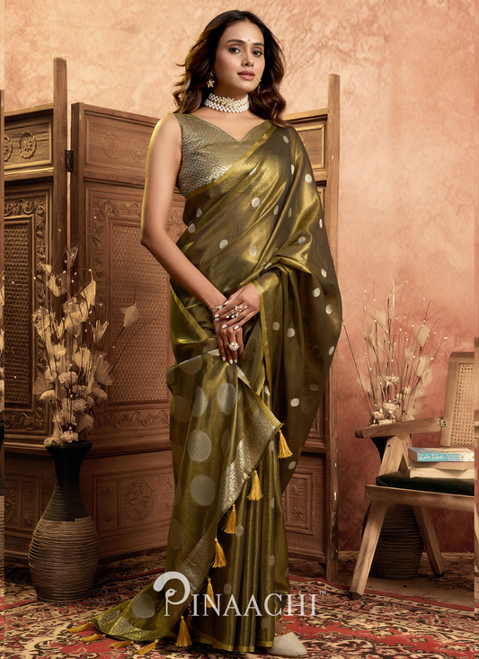 Elegant woman wearing a green and gold pinaachi tissue silk saree online with polka dot design and tassels