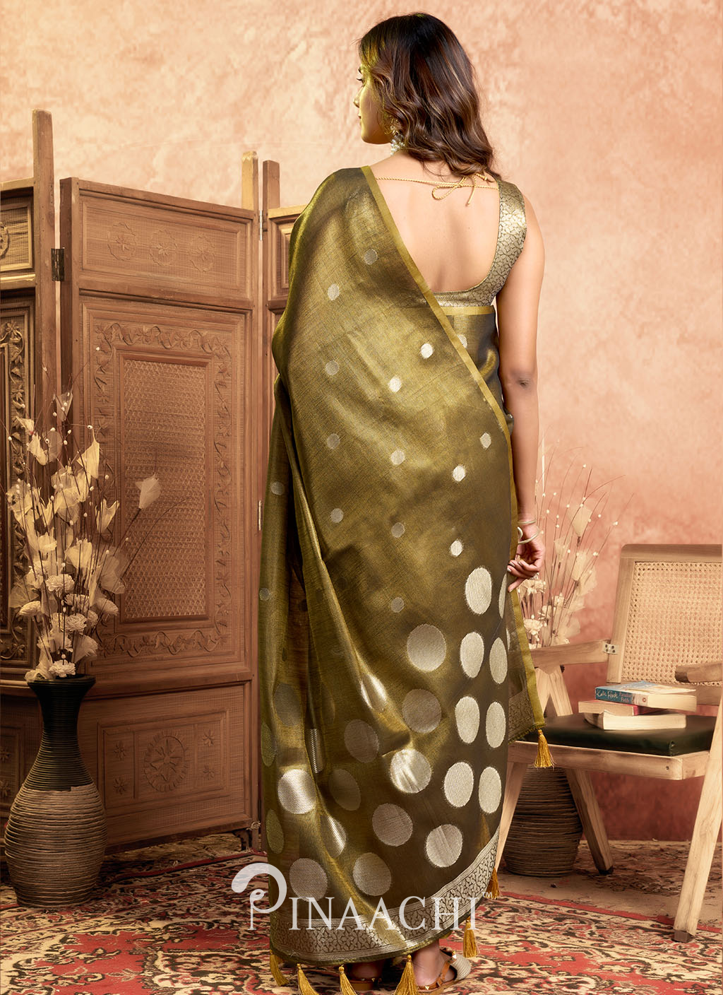 Elegant green pinaachi tissue silk saree online with gold polka dot design worn by a model indoors