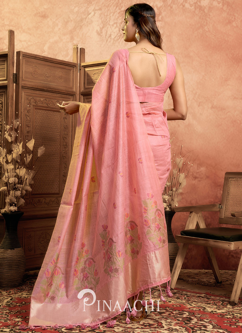 Pinaachi pink jamdani saree with floral patterns worn by model in elegant traditional setting