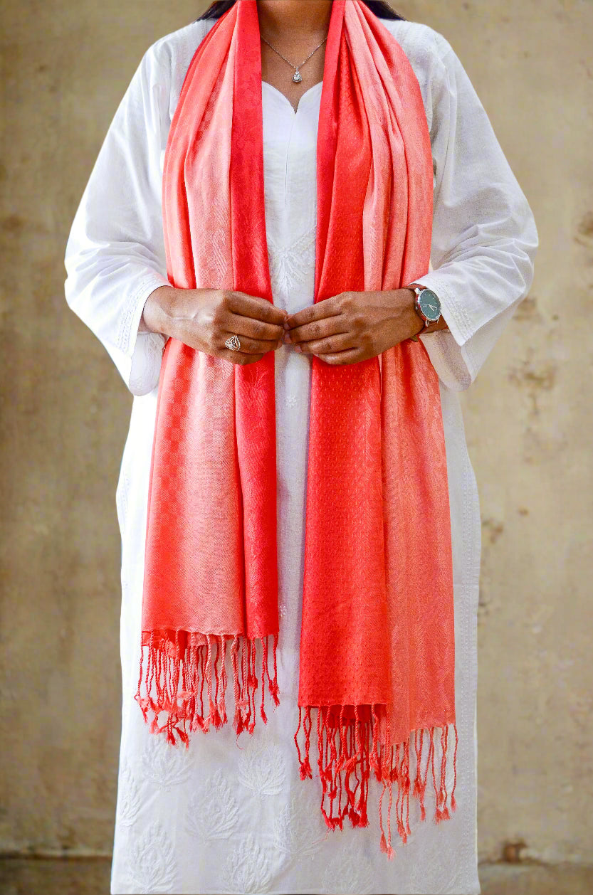 Elegant red gradient jacquard stole draped elegantly over a white outfit with fringed edges