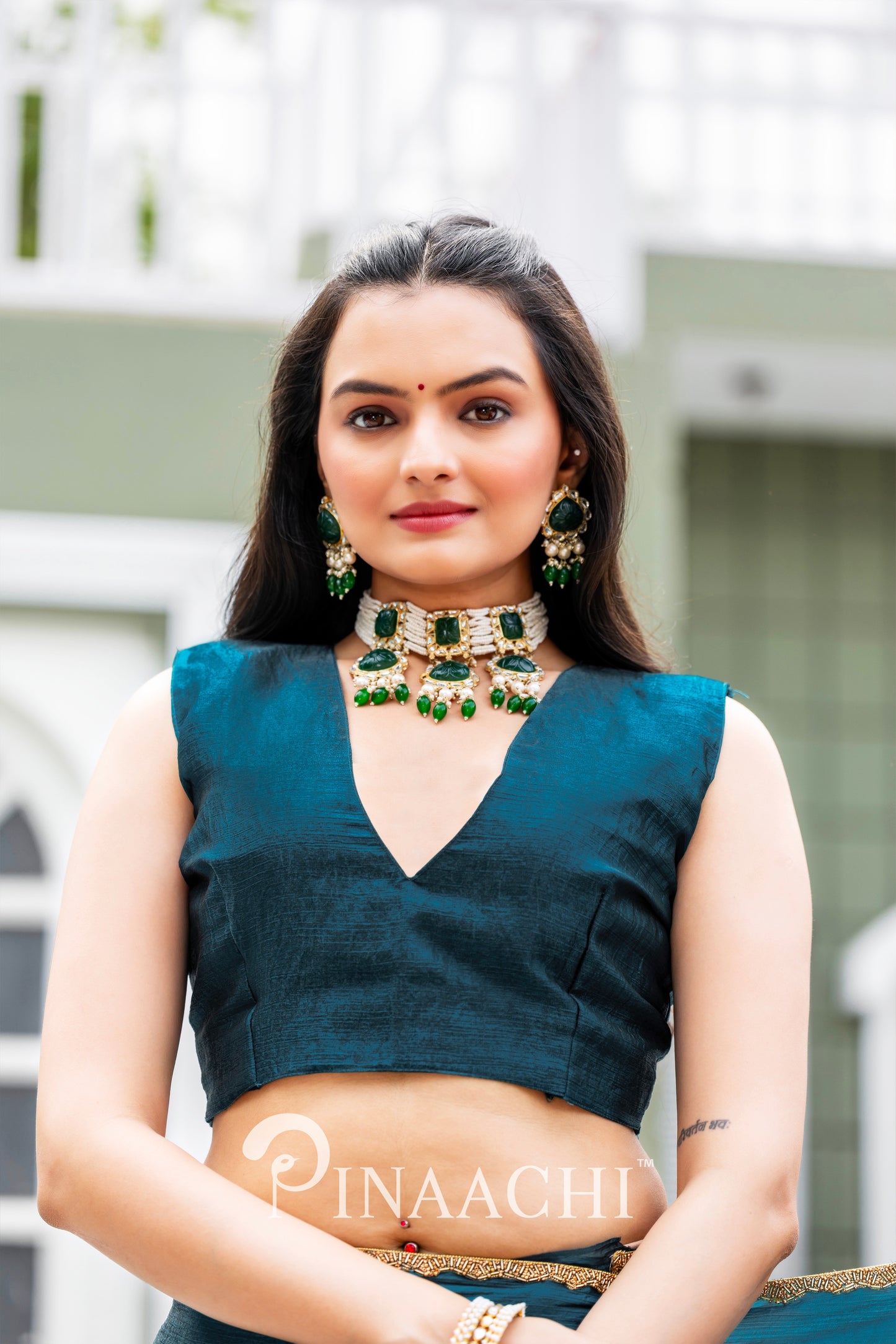 Woman wearing Pinaachi Morpich chiffon saree with a deep teal blouse and traditional green jewelry