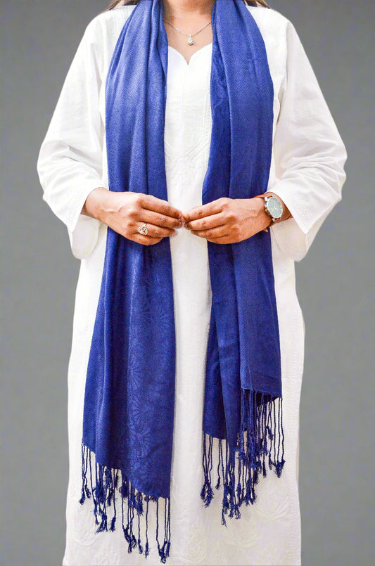 Woman draped in a blue jacquard stole with fringed edges for a stylish layering option
