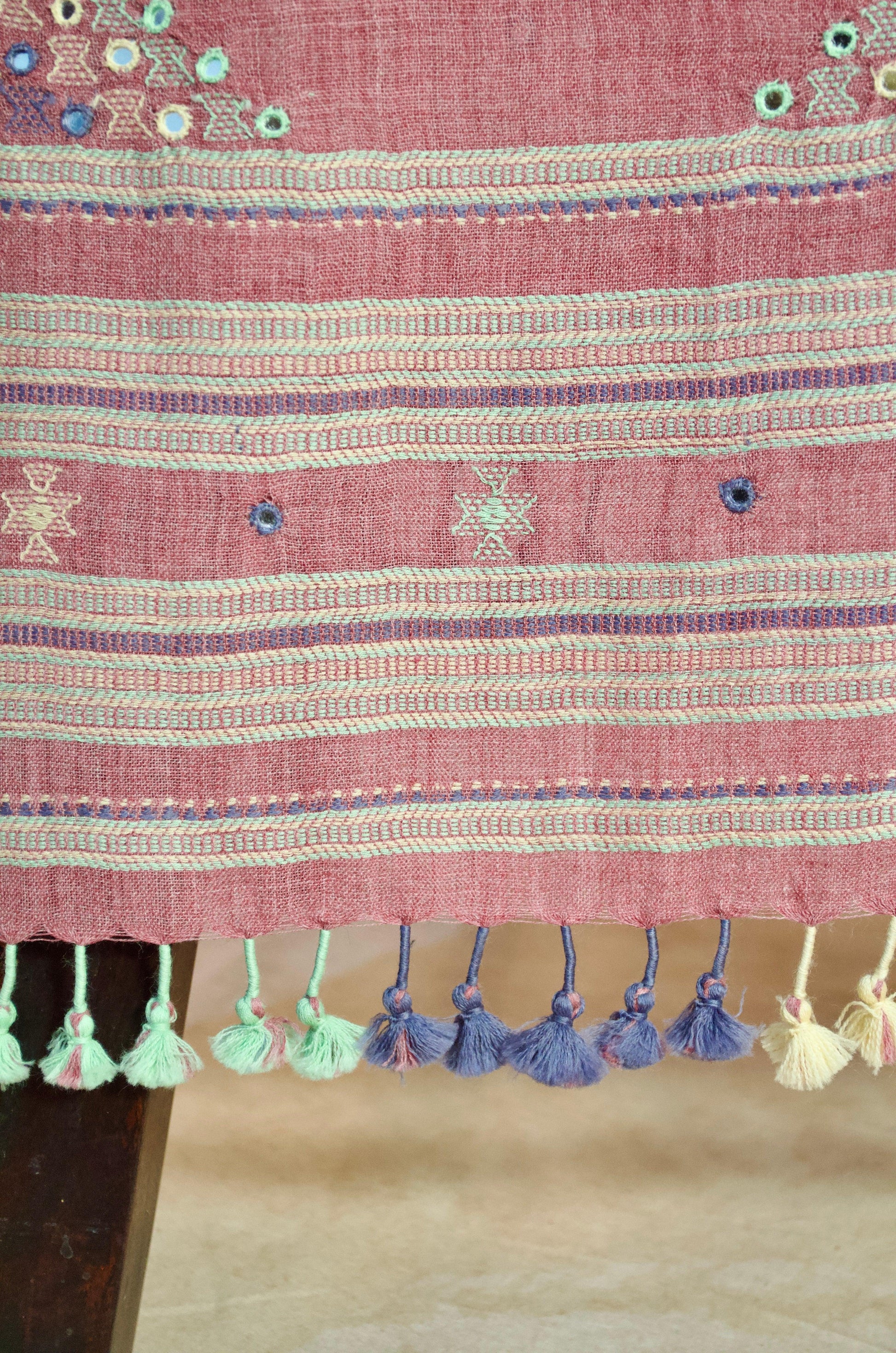 Handwoven merino wool stole with intricate embroidery and colorful tassels at the hem