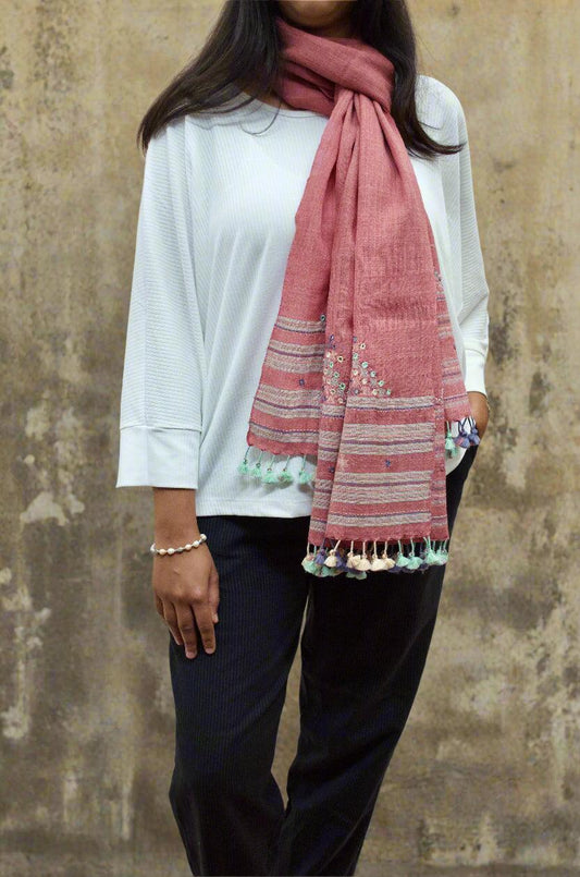 Stylish woman wearing a handwoven merino wool stole in pink with decorative tassels