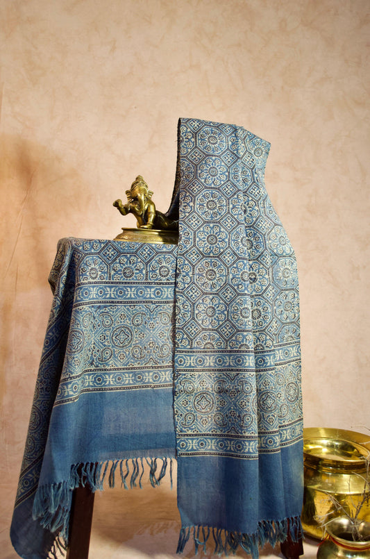 Stylish Merino wool Ajrakh stole in blue with intricate designs displayed on a wooden table