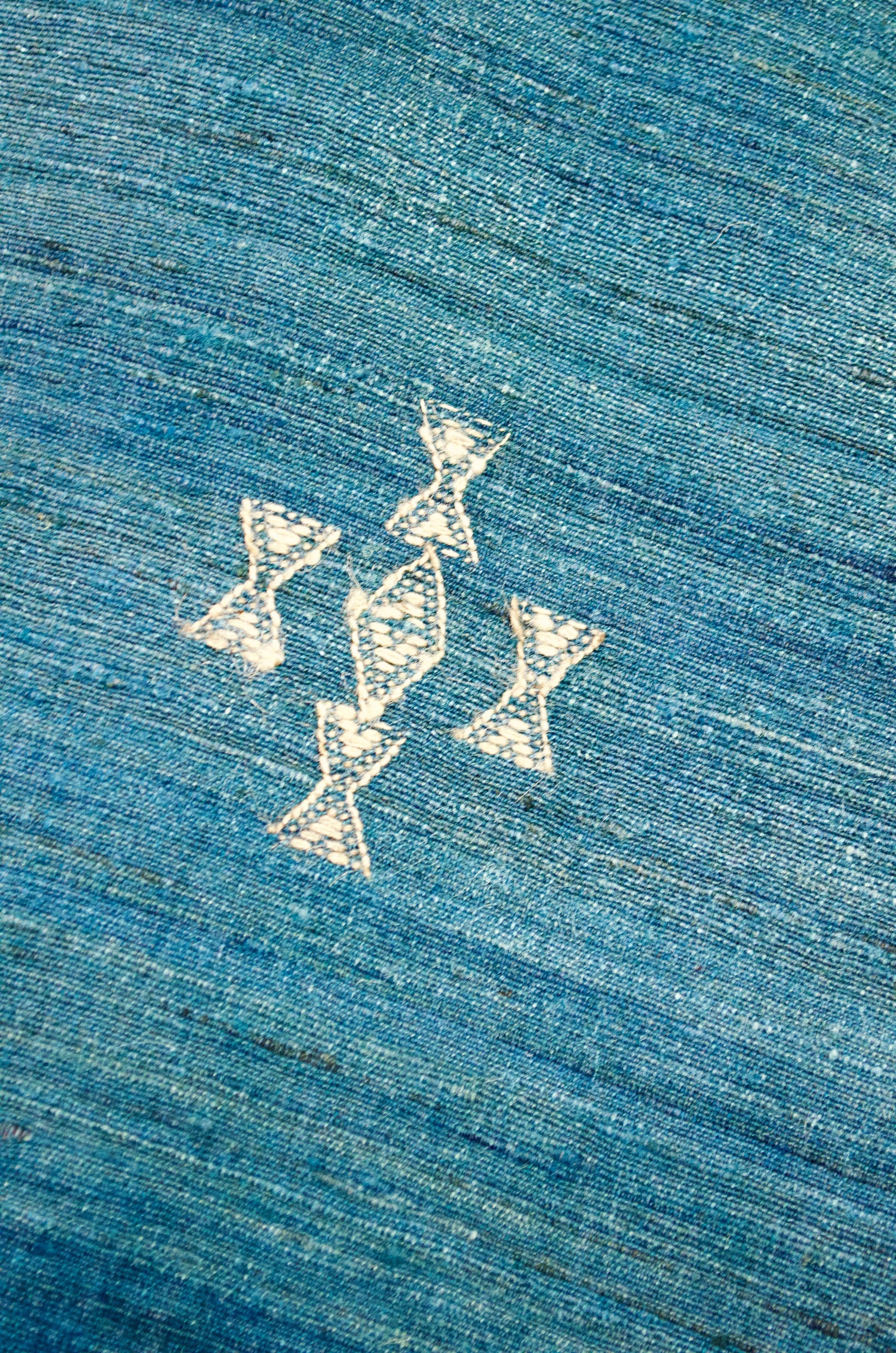 Close-up of intricate designs on a merino wool indigo shawl featuring elegant embroidery