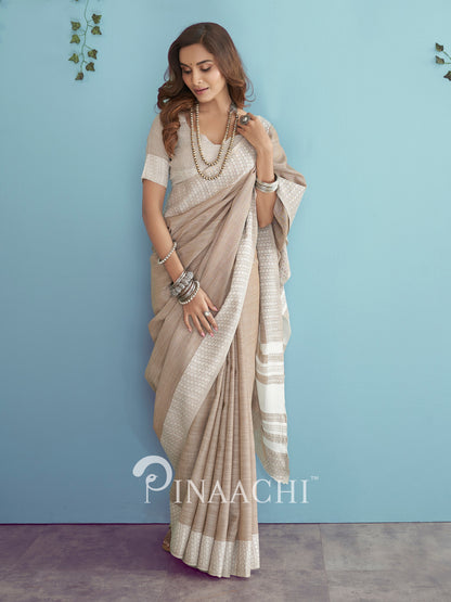 Elegant beige soft linen saree by Pinaachi, featuring intricate patterns and a graceful drape