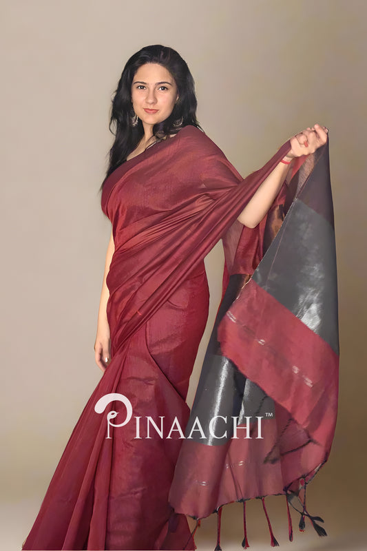 Woman wearing a brick red cotton saree with zari, showcasing elegant draping and intricate details