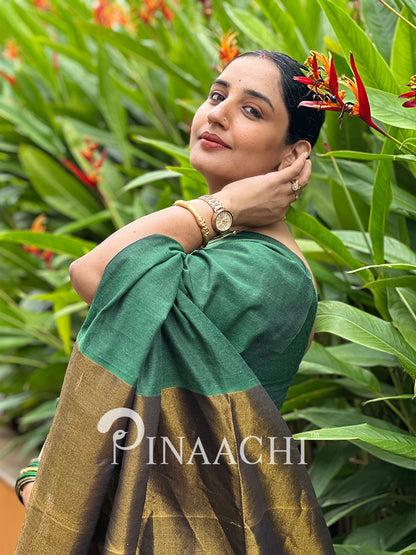 Elegant woman wearing an emerald green cotton saree with a beautiful gold border outdoors