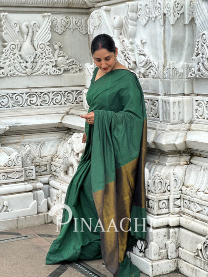 Elegant emerald green cotton saree draped beautifully with golden border details for a sophisticated look