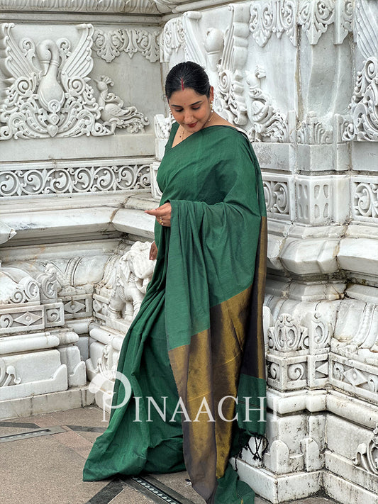 Elegant emerald green cotton saree draped beautifully with golden border details for a sophisticated look