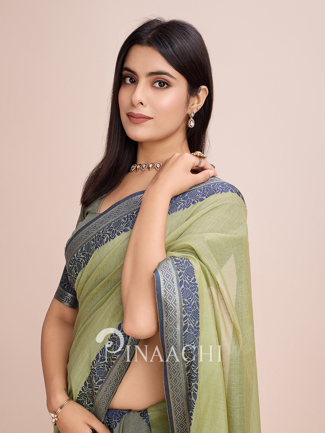 Pinaachi green cotton saree with woven border, elegantly draped, showcasing intricate designs