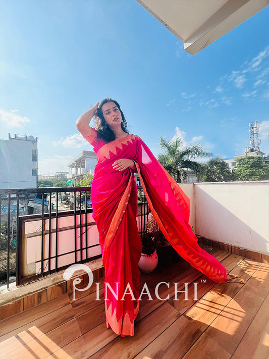 Woman in a pink saree on a balcony with a clear blue sky