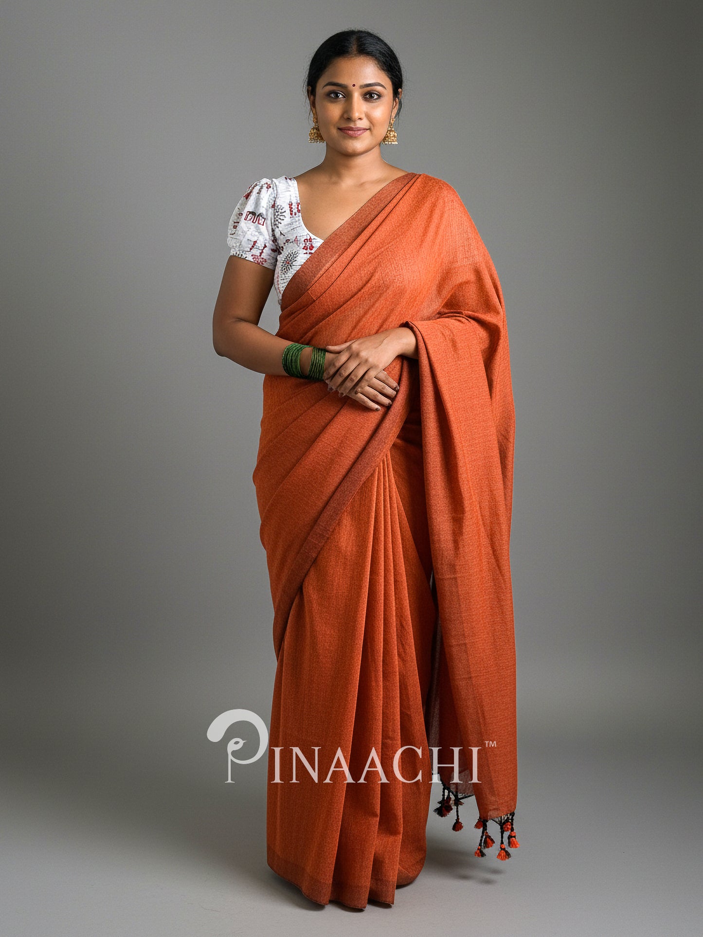 Stylish model wearing a handspun rust orange cotton saree draped elegantly with a traditional blouse