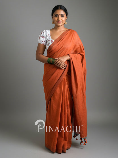 Stylish model wearing a handspun rust orange cotton saree draped elegantly with a traditional blouse